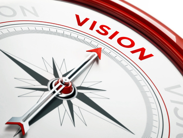 Arrow of a compass is pointing vision text on the compass. Arrow , vision text and the frame of compass are metallic red in color. White background. Horizontal composition with copy space. Vision concept.